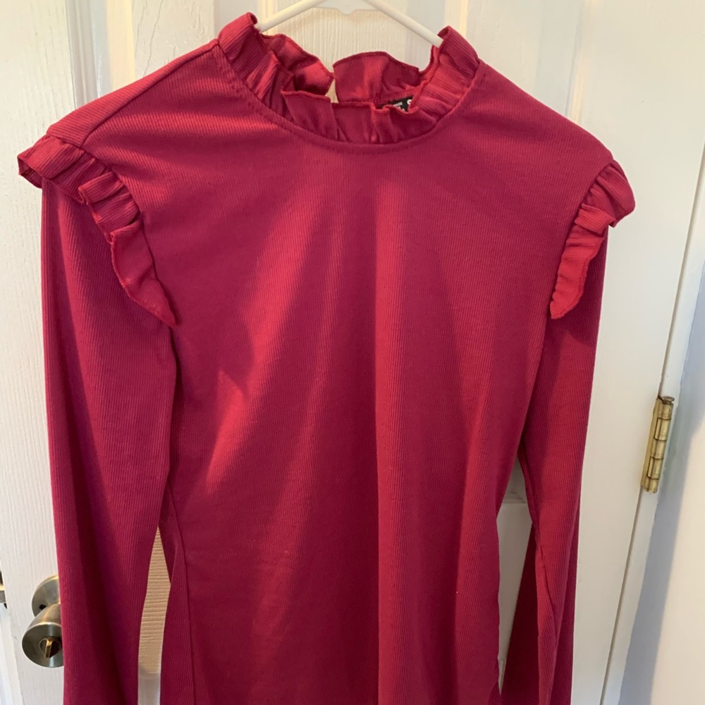 Long sleeve pinkish purple color shirt with ruffles and peep hole in the back.